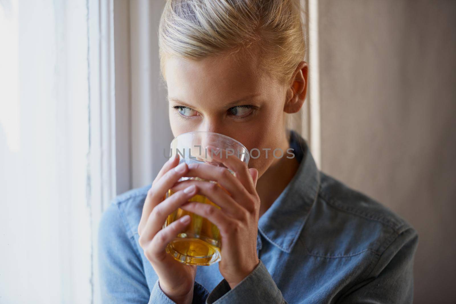 Having a relaxed day at home. A young woman drinking tea while standing at her window. by YuriArcurs