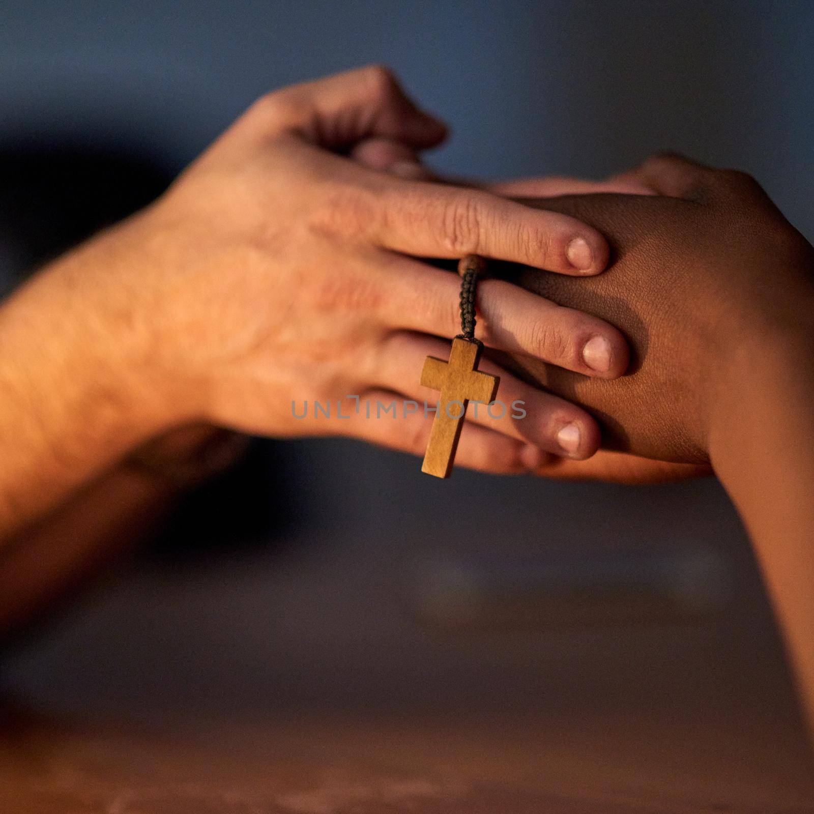 Closeup shot of a two people holding hands in support with a rosary.
