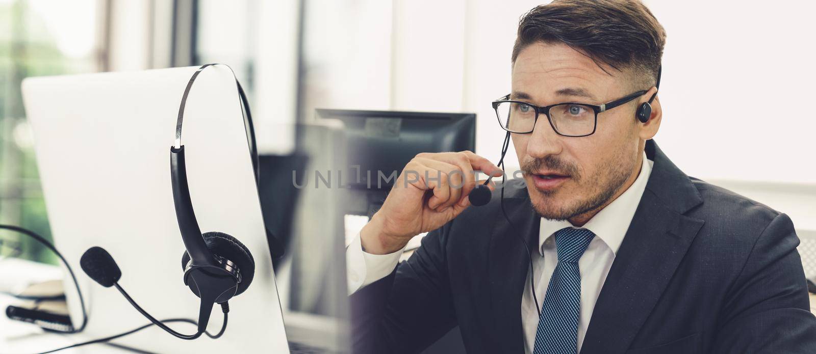 Business people wearing headset working in office to support remote customer or colleague. Call center, telemarketing, customer support agent provide service in broaden view .