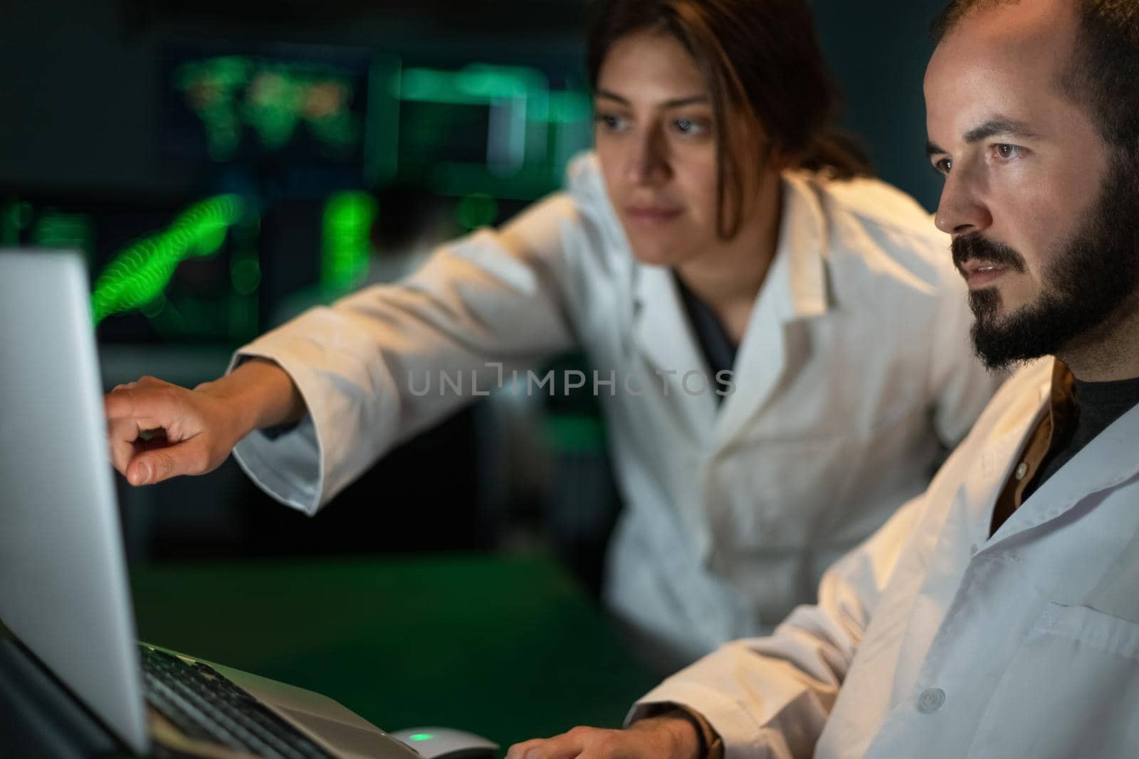 Female scientist shows male doctor colleague some experiment results in the laptop. Working in laboratory. Science and technology concept.