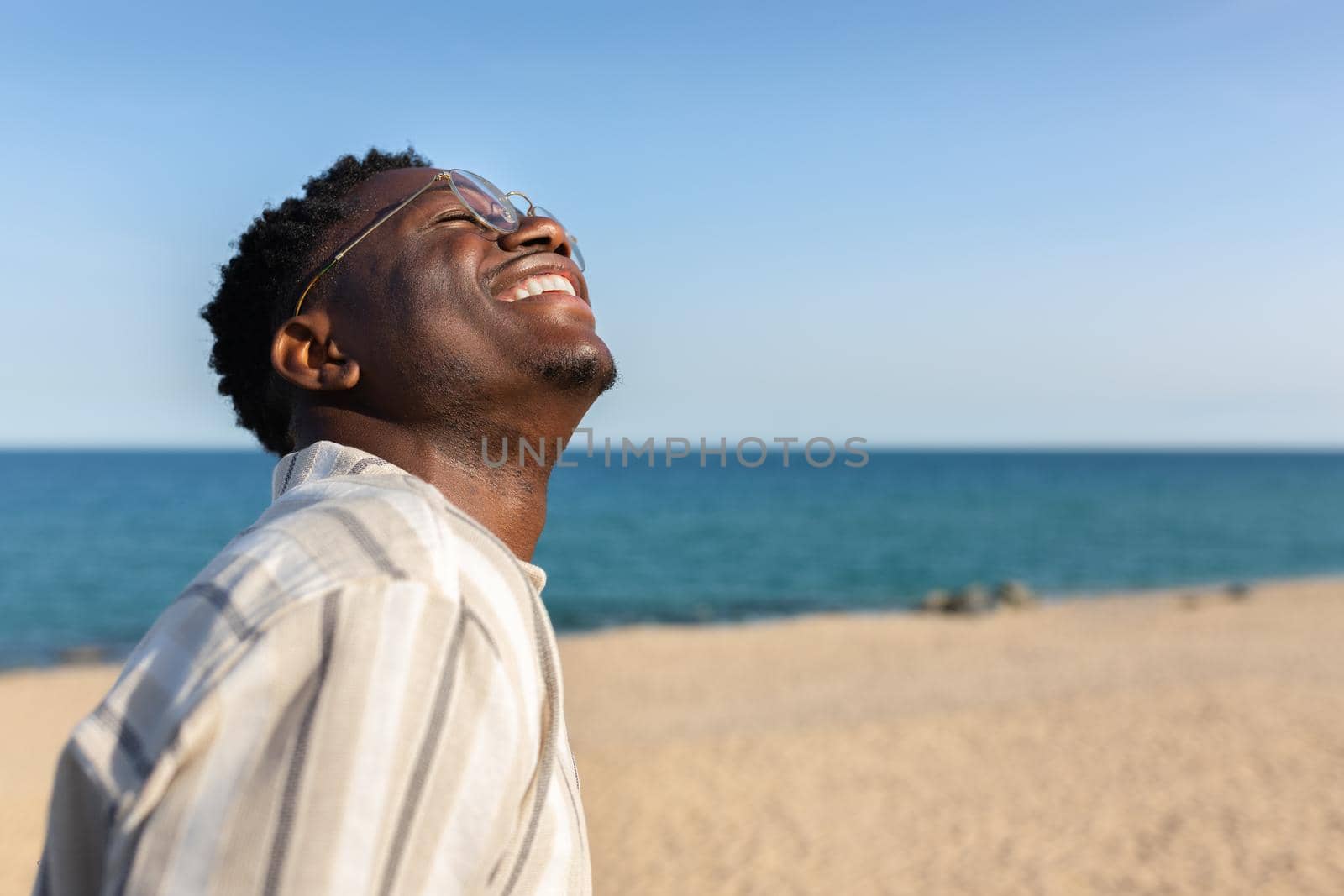 Happy young black man smiling. African american man enjoying holidays on the beach. Copy space. Vacation trip concept.