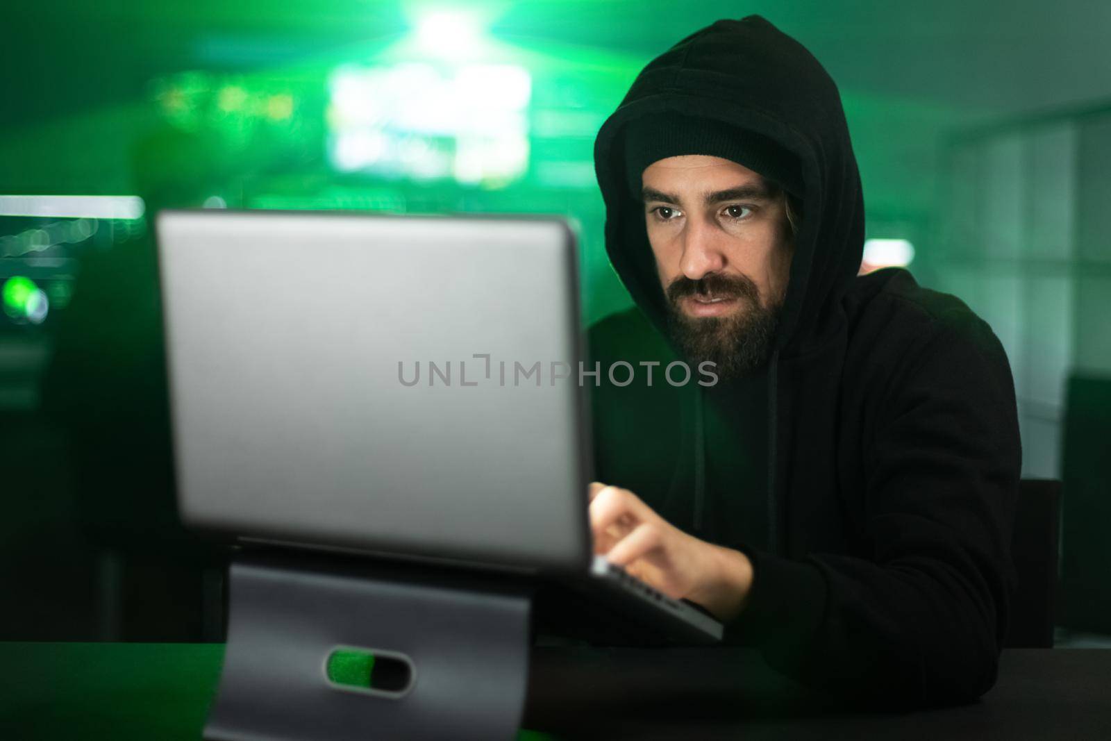 Male black hat hacker hacking security firewall late in the office. by Hoverstock