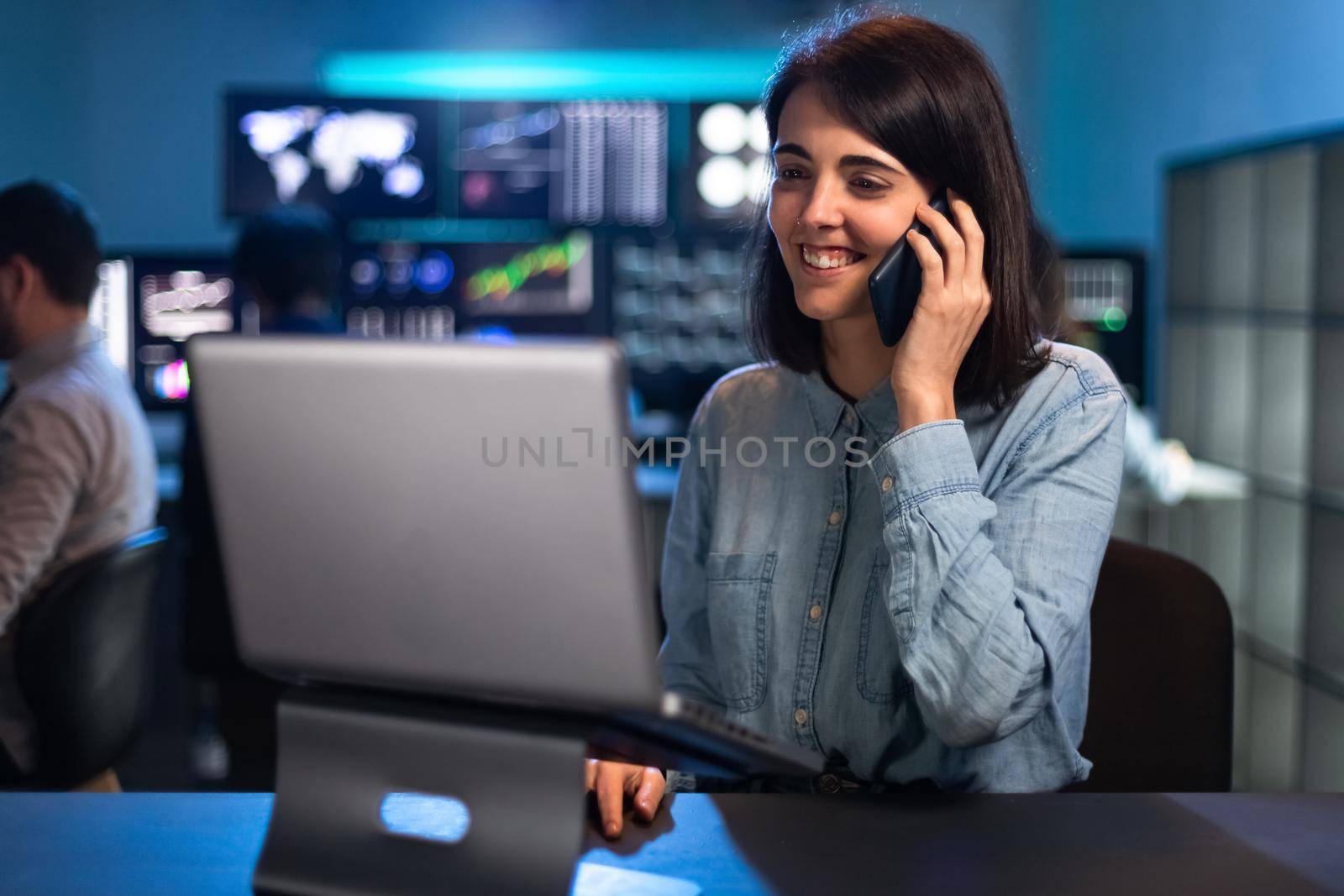 Female stock market trader working in office using laptop and talking on the phone with client. Financial adviser concept.