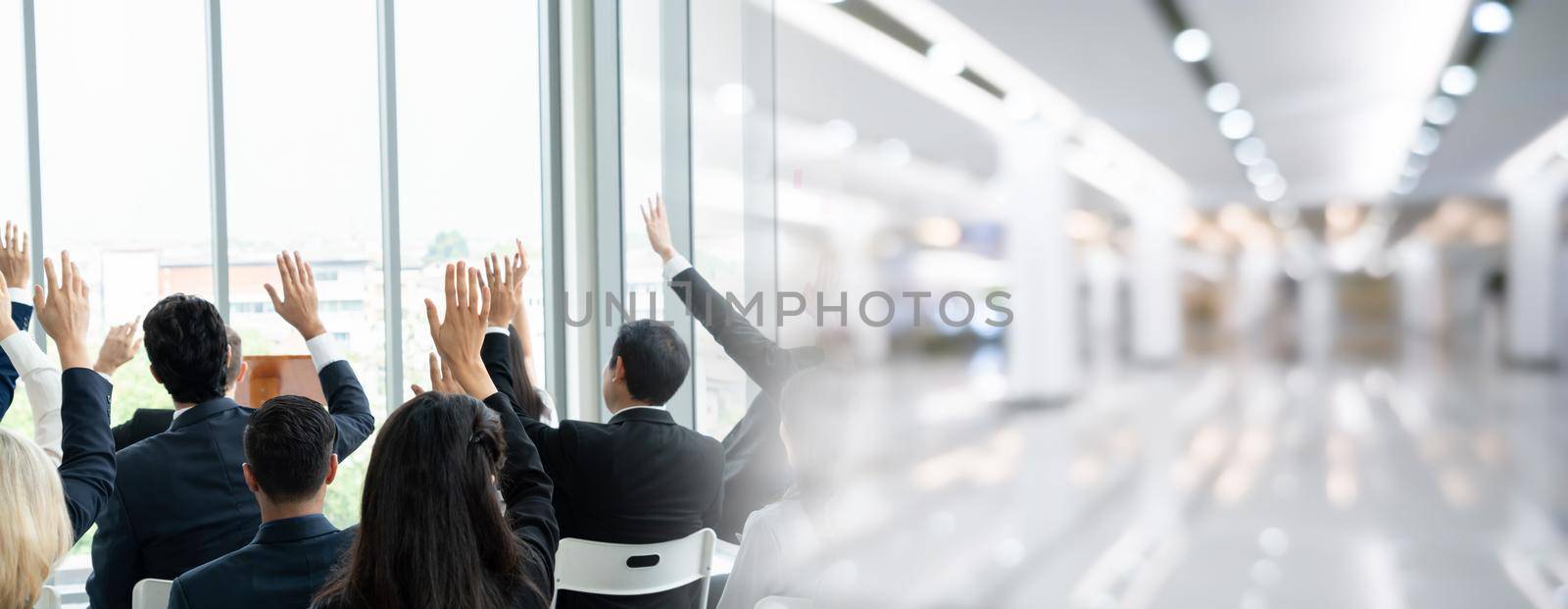 Group of business people meeting in a seminar conference widen view . Audience listening to instructor in employee education training session . Office worker community summit forum with speaker .