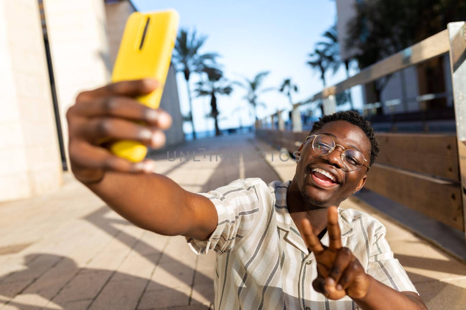 Young black man taking selfie using phone making peace sign. Happy, African american male having fun. Social media concept.