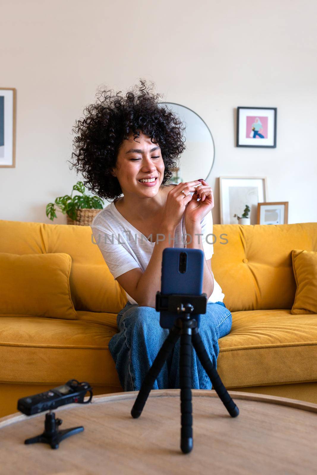 Vertical portrait of African American mixed race influencer woman on live stream, recording video for social media. Technology concept.