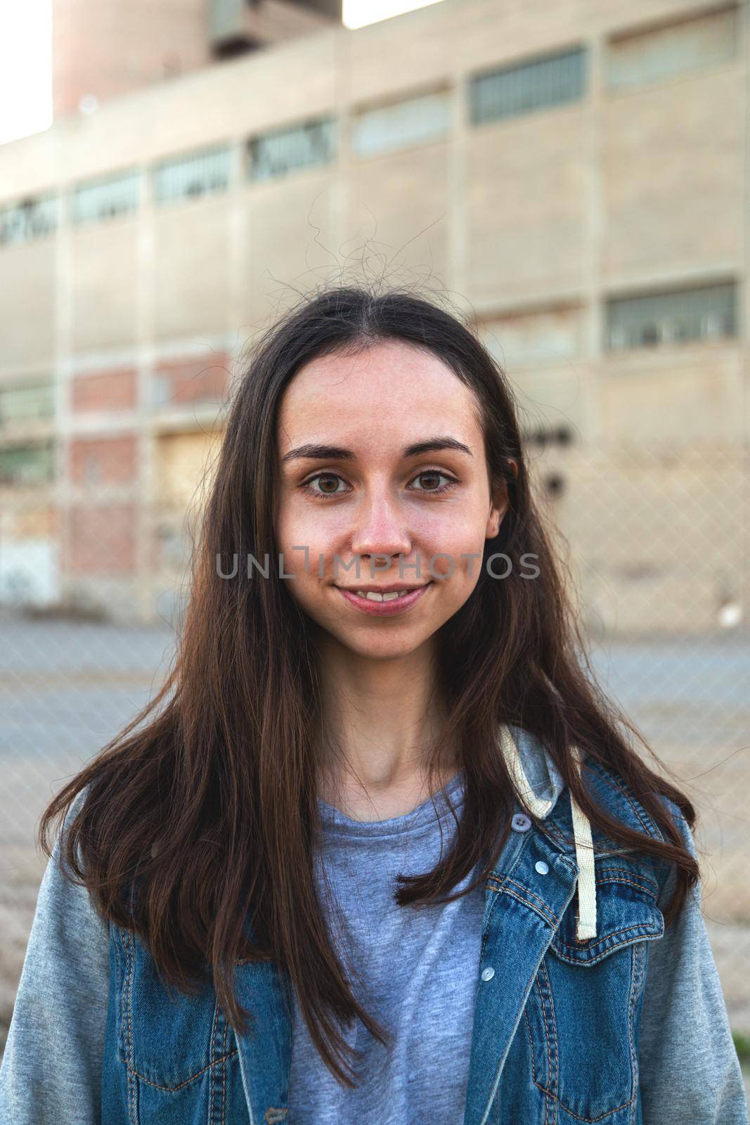 Vertical portrait of smiling caucasian girl with long hair looking at camera. Headshot.