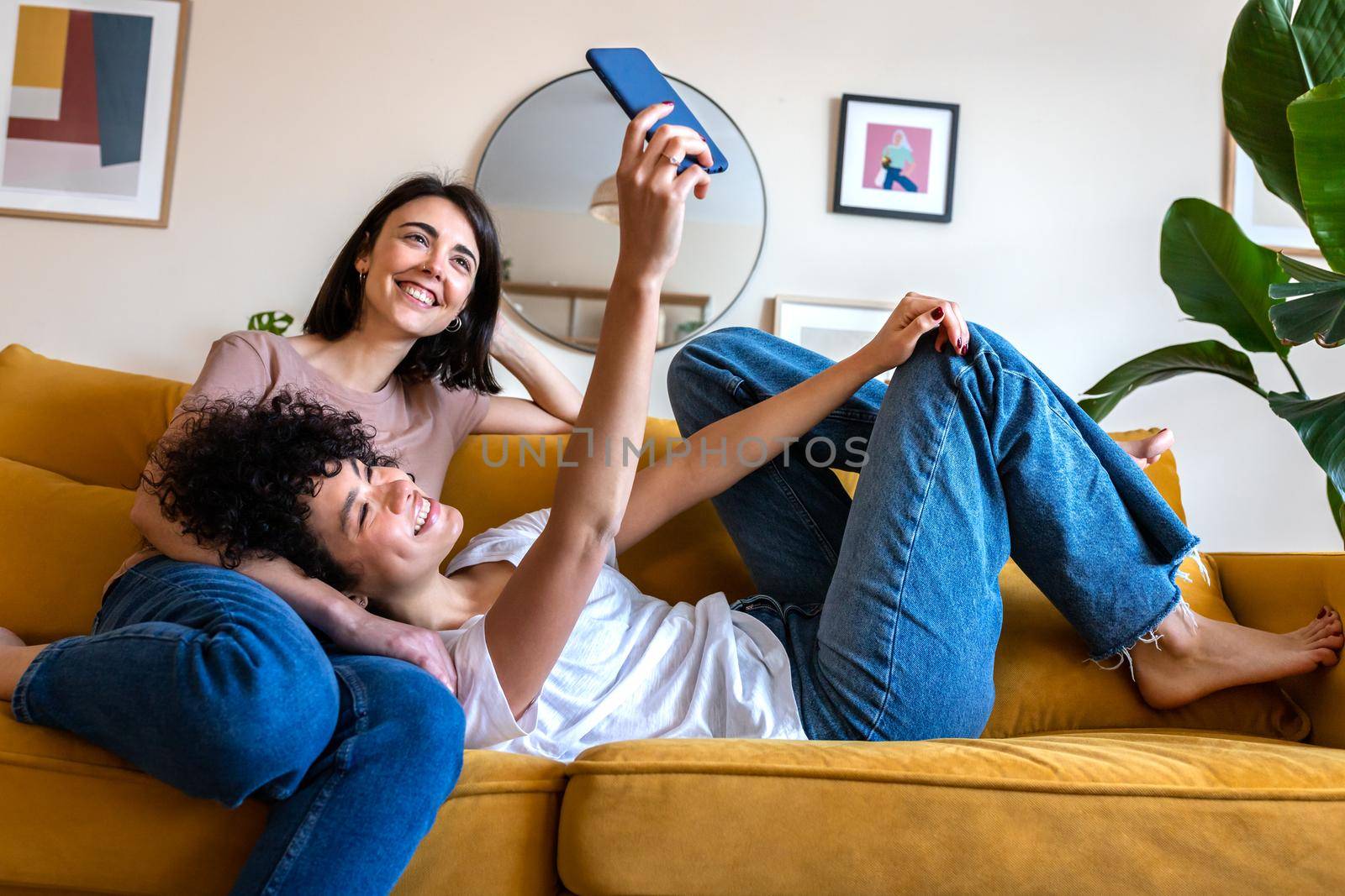 Young lesbian couple taking selfie at home using mobile phone. Technology and lgbtq concept.