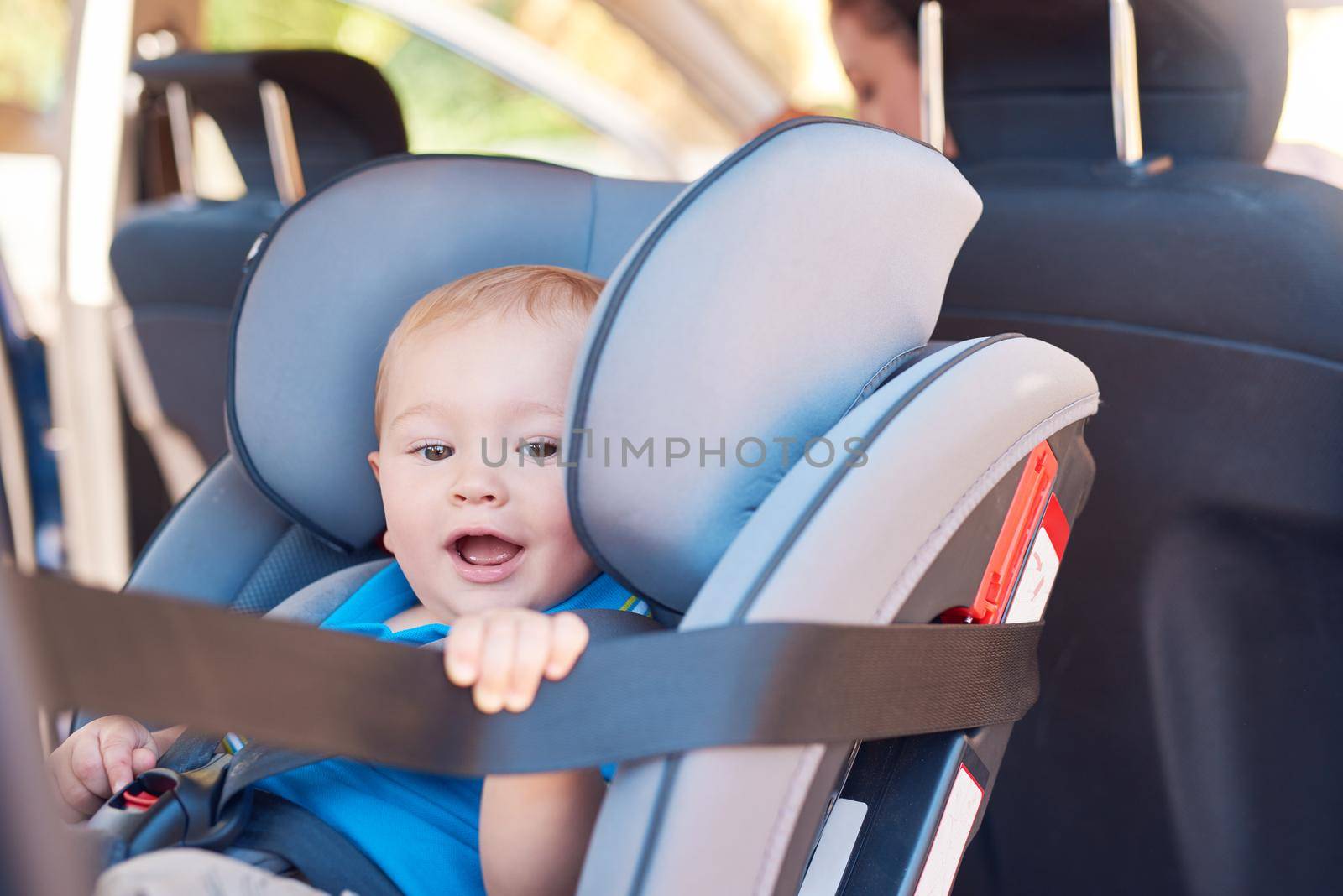 Im off on an adventure with Mom. Cropped shot of a mother sitting in a car with her baby boy in a car seat. by YuriArcurs