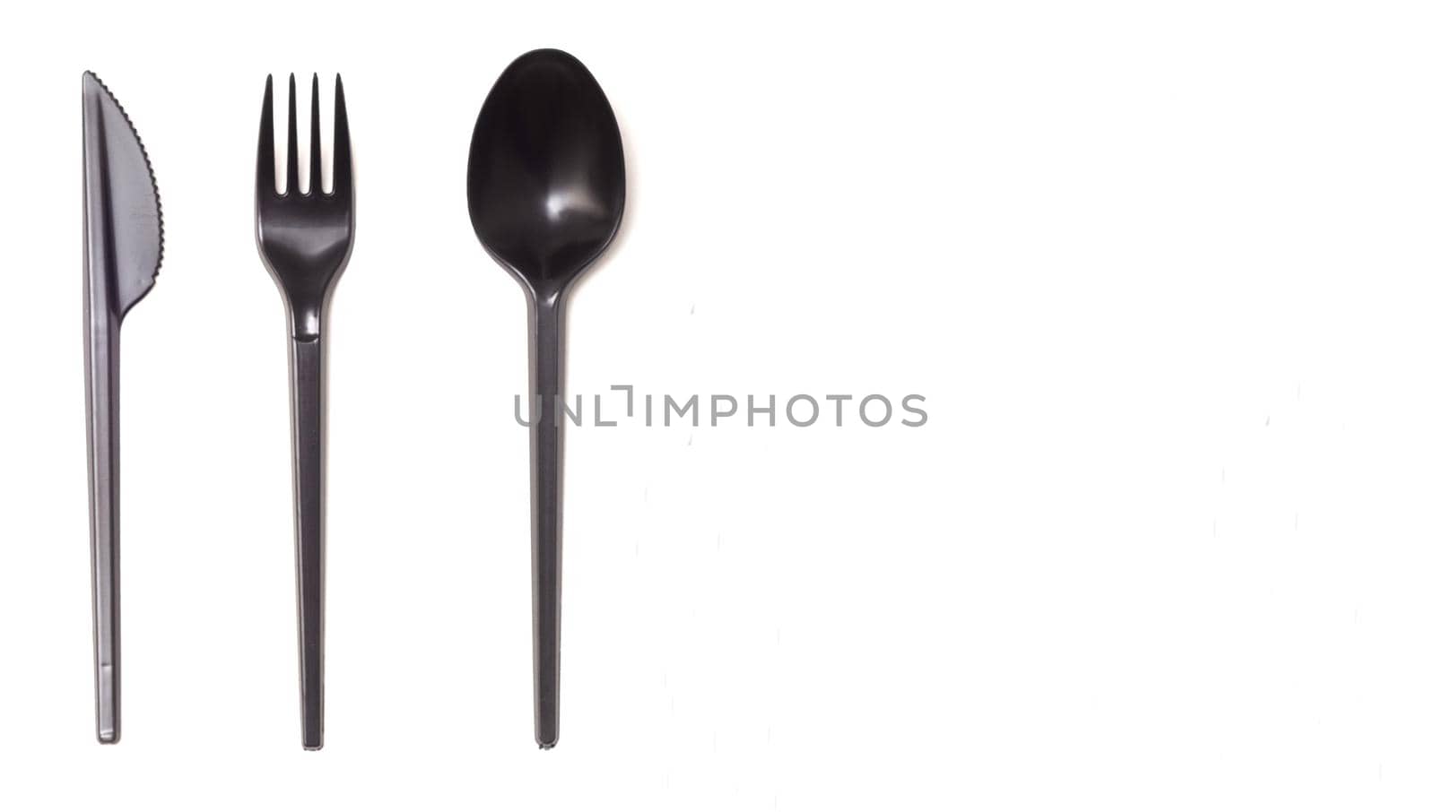 Repeating black plastic disposable knife,spoon on white background, copyspace.