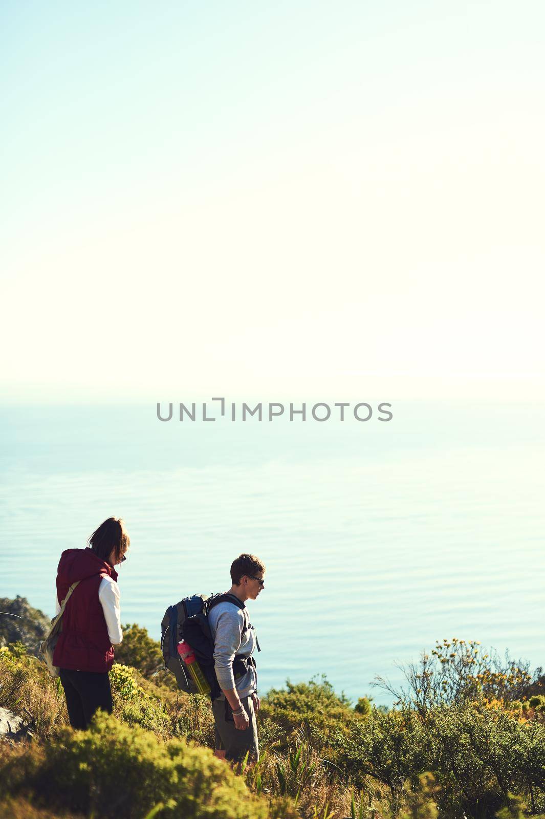 The mountains are calling. Shot of a young couple exploring the outdoors on a hiking trail. by YuriArcurs