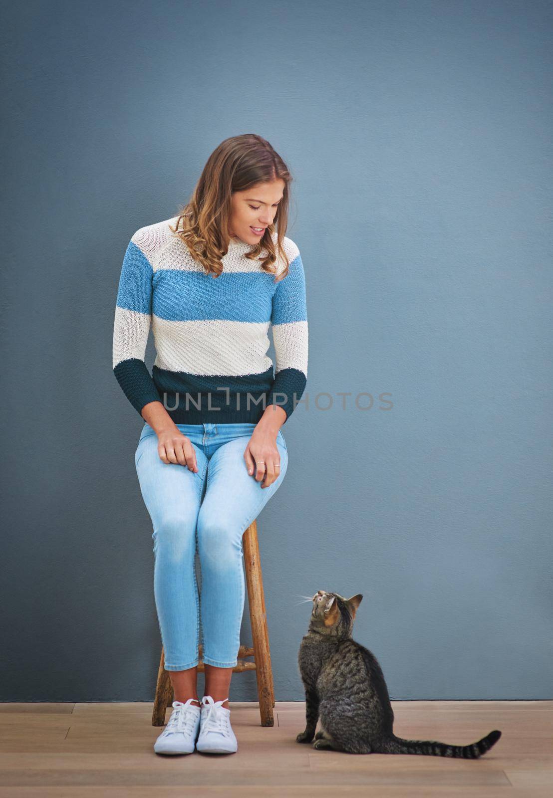 Hi kitty. Shot of a young woman looking at a cat. by YuriArcurs