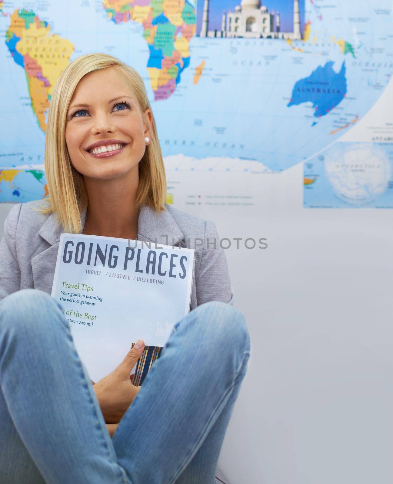 A beautiful young woman dreaming about an overseas trip while holding a travel magazine.