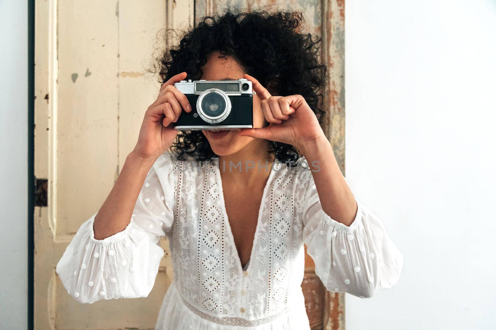 Young multiracial woman taking a picture with retro style analog camera. Vintage photography concept.