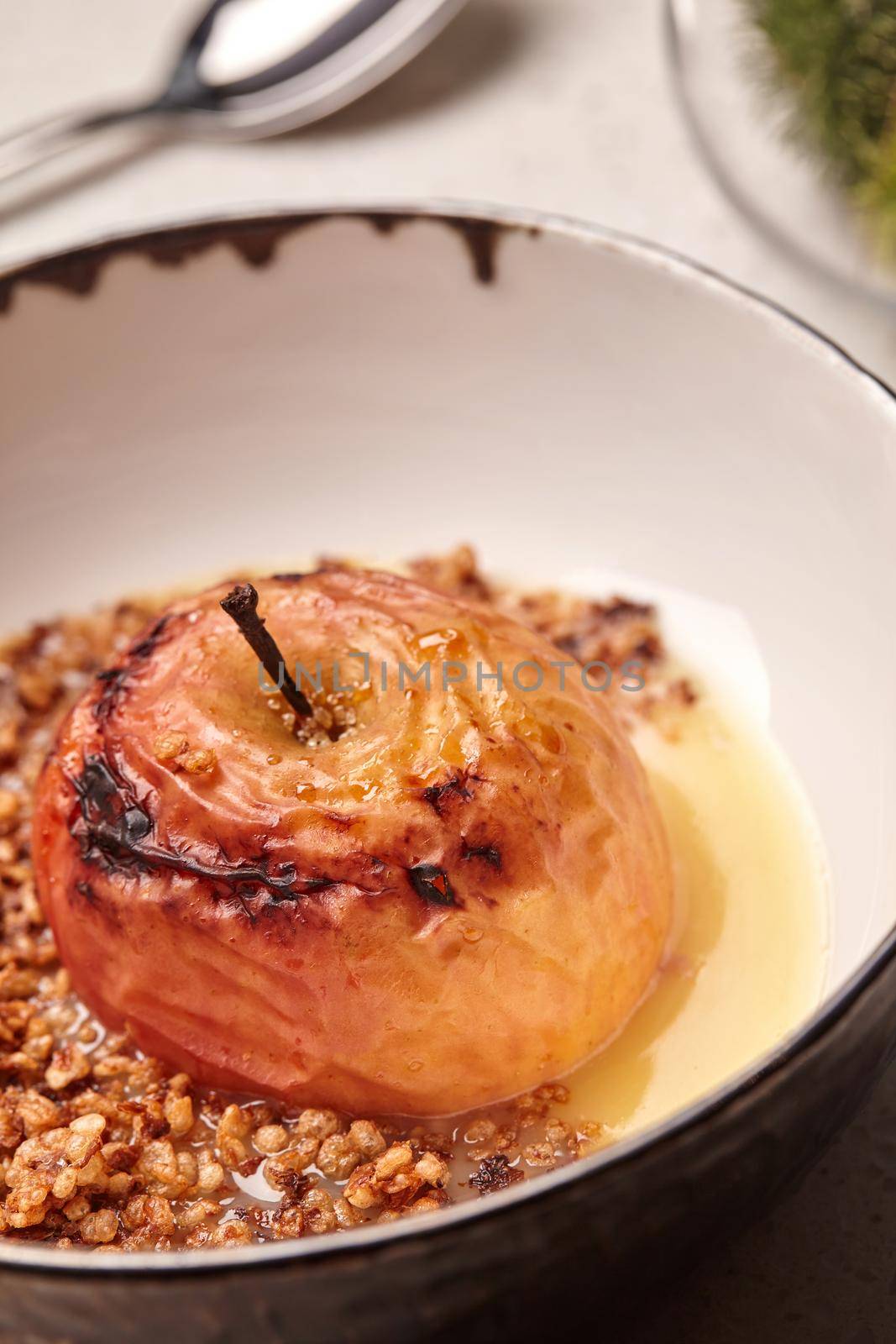 Close-up photo of a gourmet baked apple stuffed with honey and nuts, healthy nutrition, delicious sweet food, gorgeous fruit dessert flavored with cinnamon. Autumn or winter dessert. Served in a deep bowl. Cooking concept.