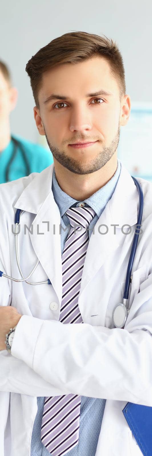 Two male medical workers in uniform at the workplace, close-up, vertical photo. Cooperation, team, clinic staff