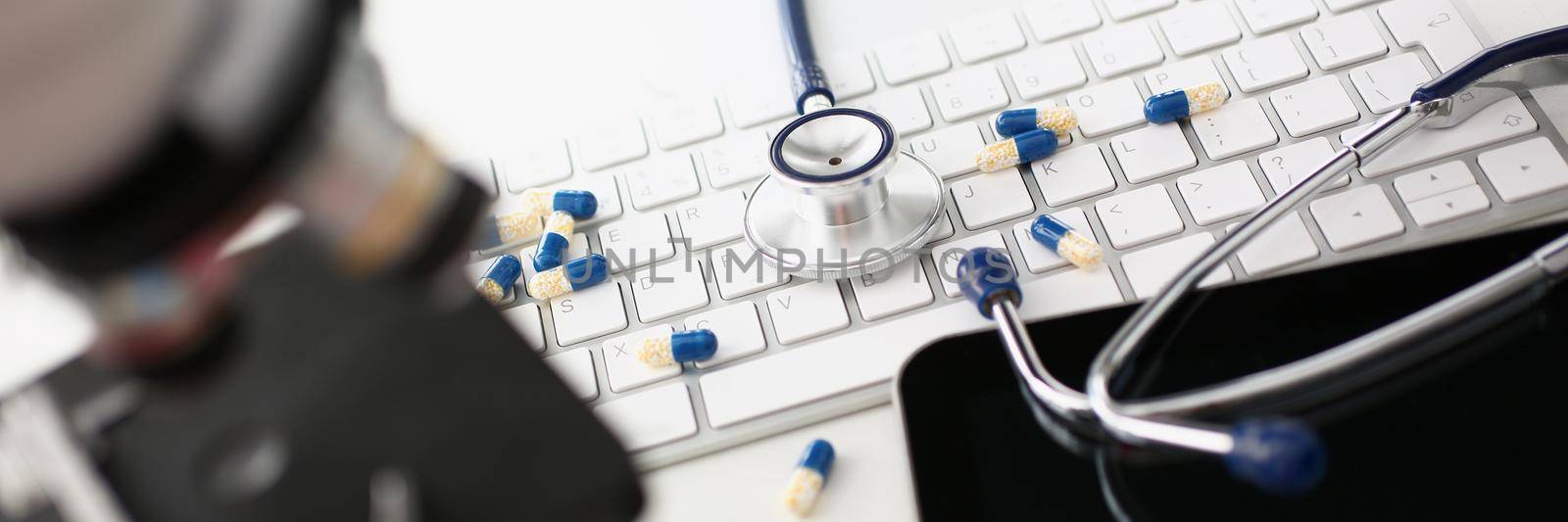 On the keyboard are capsules and a stethoscope, a workstation for a consultant doctor. Online medicine, consultation and analysis