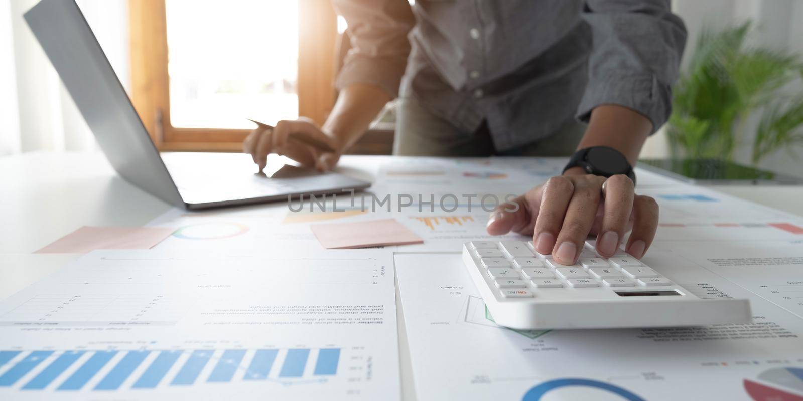 Close up businessman hand using calculator and working with laptop calculate about finance accounting at coffeeshop outdor.finance accounting concept by wichayada