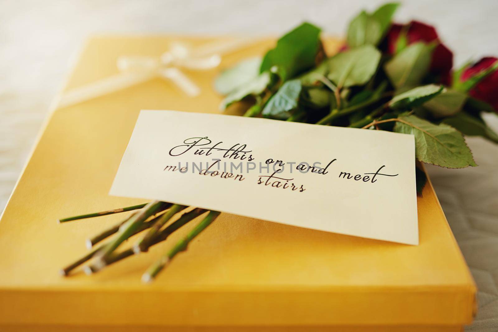 Say I love you with a romantic surprise. Shot of a surprise gift and bouquet with a note attached to it. by YuriArcurs