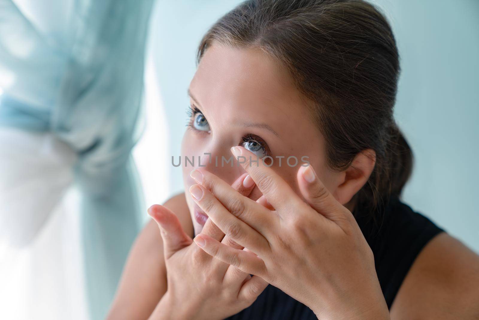 Young grl pulled back her lower eyelid and brought contact lens to her eye to put by Laguna781