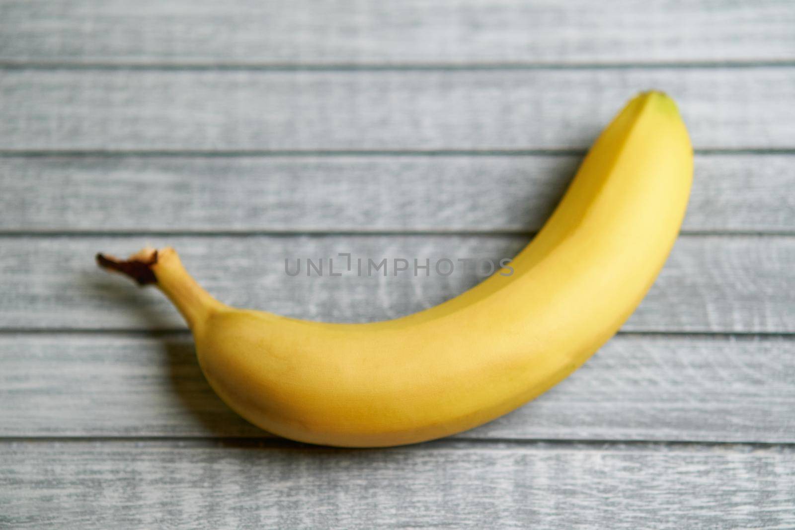 Yellow banana lays on a gray wooden background
