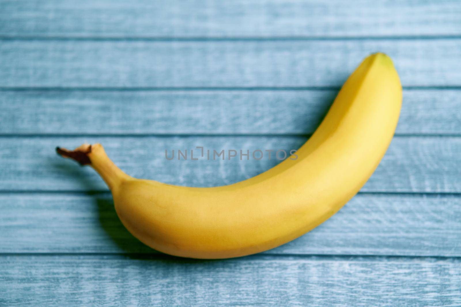 Yellow banana lays on a blue wooden background