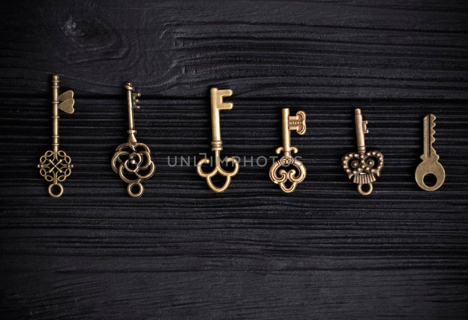 set of antique copper keys lie in a row on a black wooden background. Decorative keys pendants. The concept of the selection of the key to the heart. space for text. High quality photo