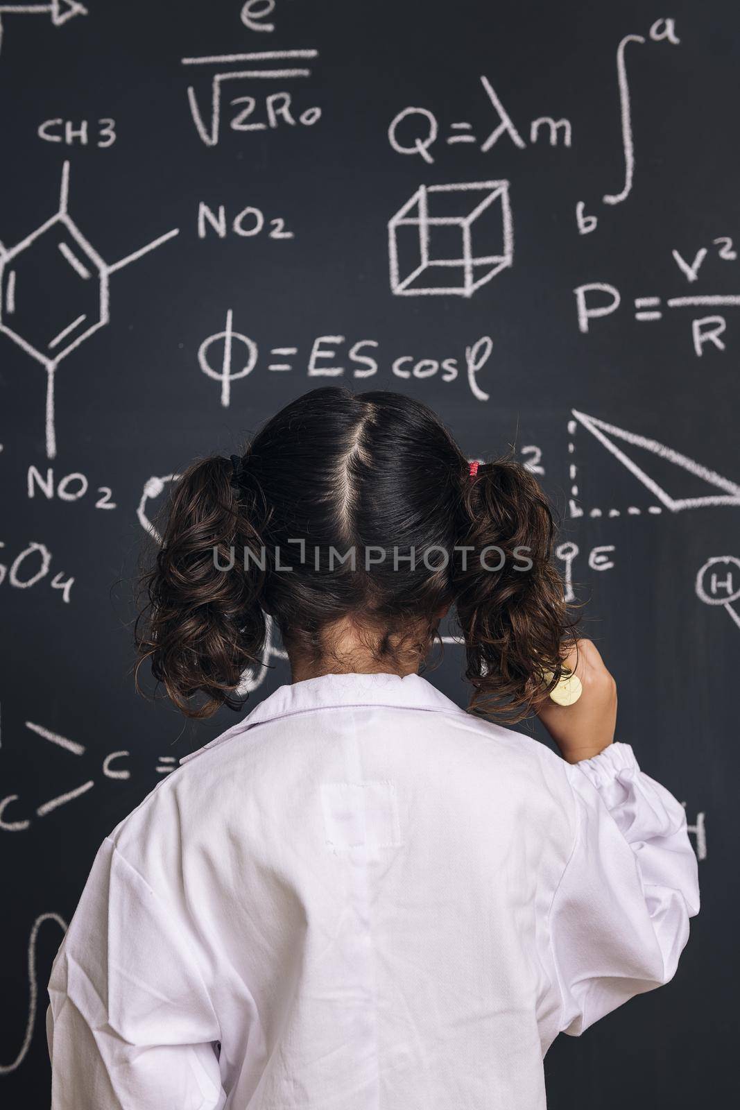child scientist in lab coat writing on blackboard by raulmelldo