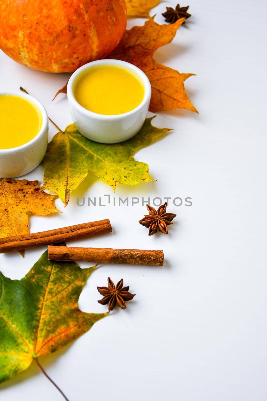 Autumn food. Pumpkin puree soup, leaves. Autumn harvest, pumpkins, leaves on grey as abstract background. Thanksgiving day. Seasonal food. Vegetarian