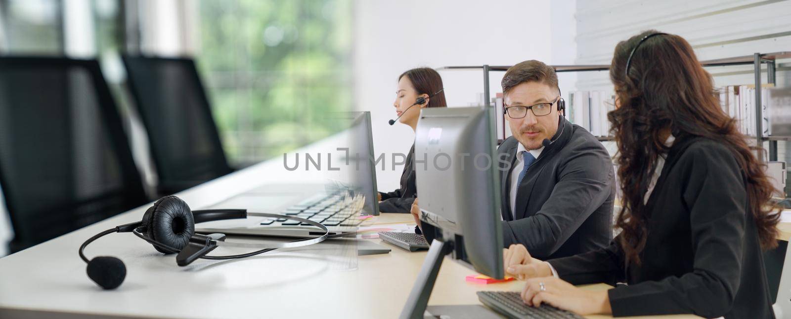 Business people wearing headset working in office to support remote customer or colleague. Call center, telemarketing, customer support agent provide service in broaden view .