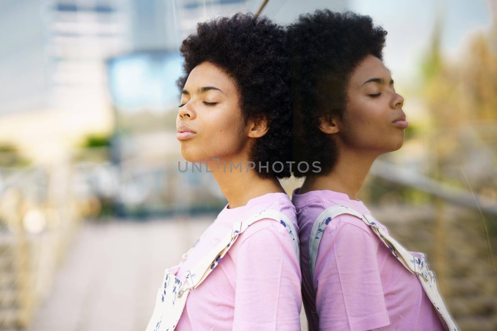 Thoughtful African-American woman with her eyes closed in a relaxed attitude on an urban background.