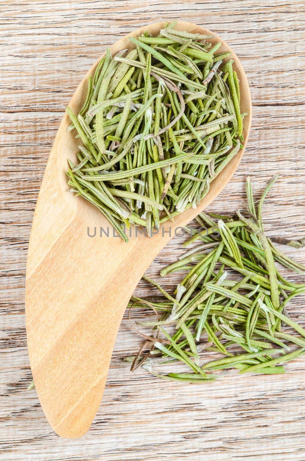 Dried rosemary spice in wooden spoon. Macro with shallow depth of field. by Gamjai