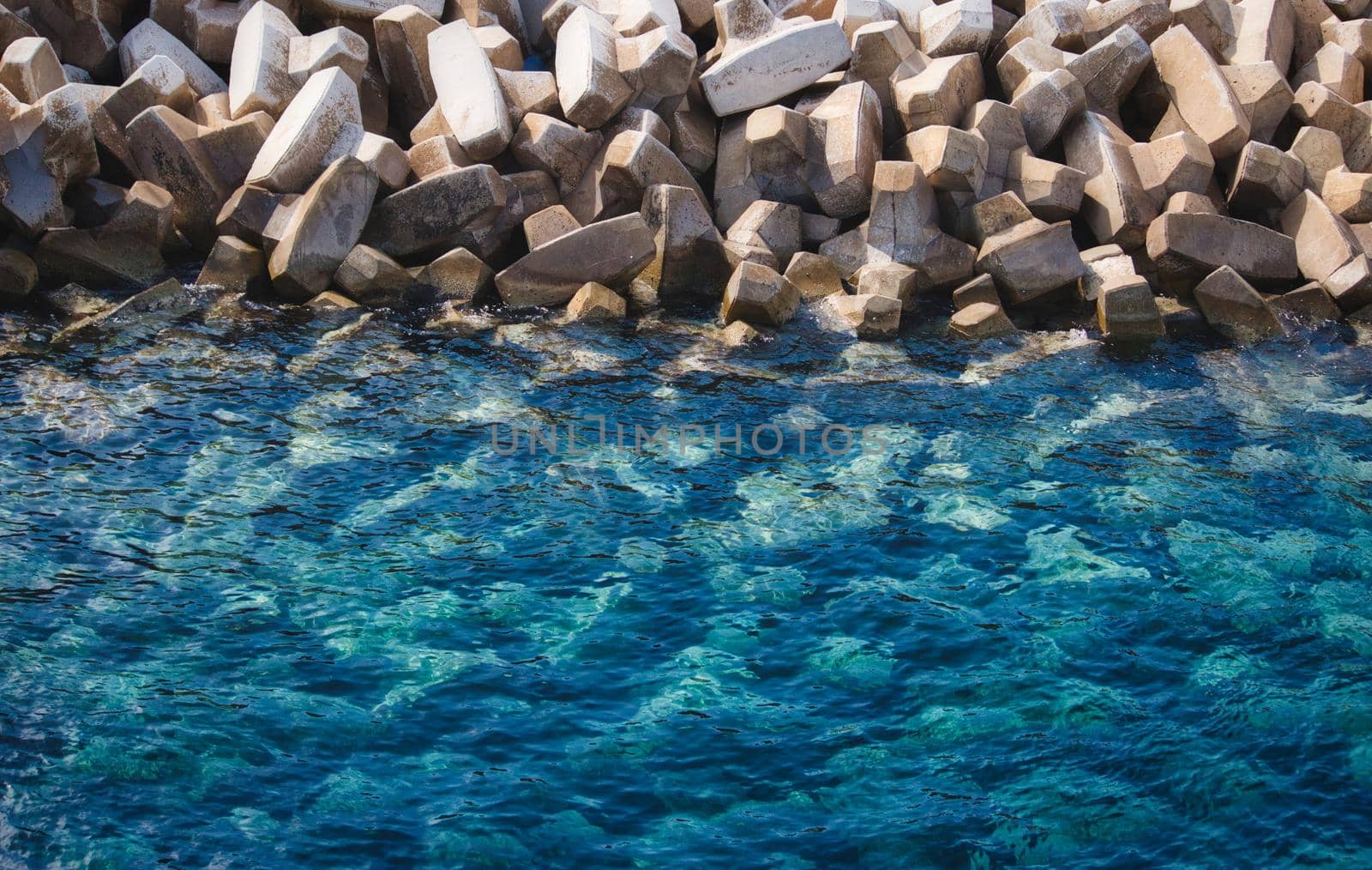 Textured background of clear blue sea and white stone tetrapods used to prevent erosion