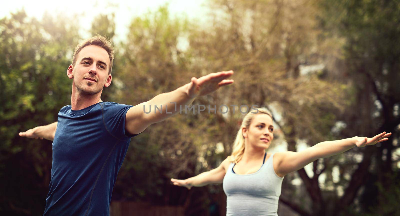 Pushing their stresses away through yoga. Shot of a young couple practising yoga together outdoors. by YuriArcurs