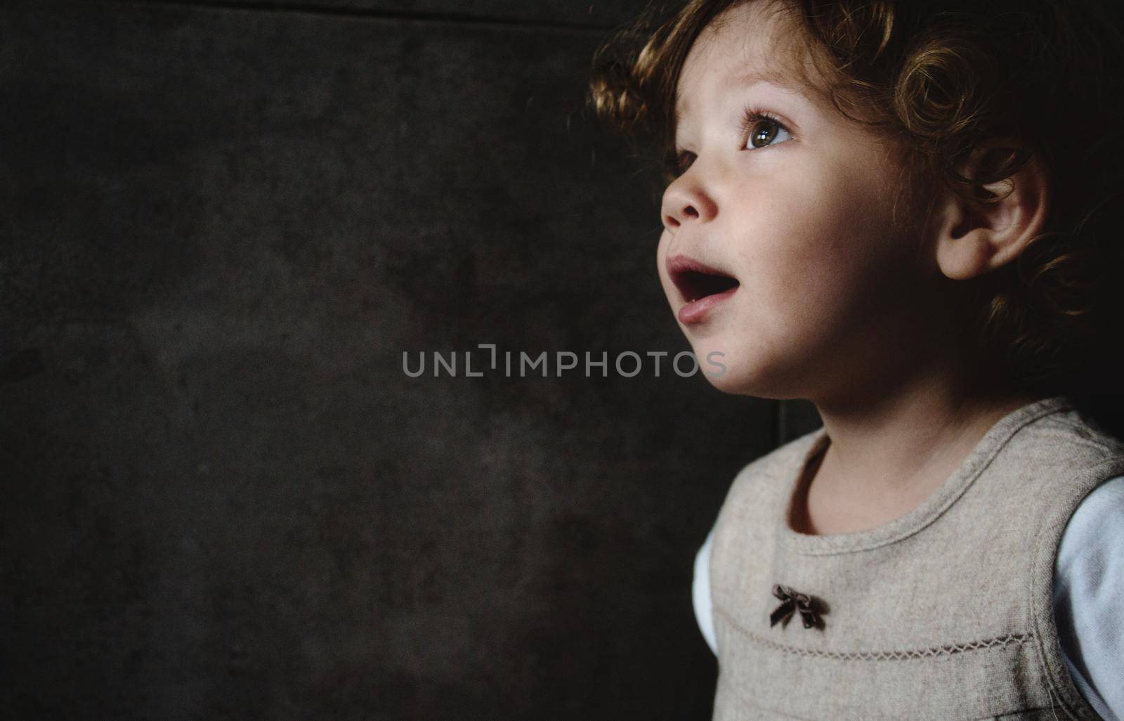 Beautiful young girl looking away against a dark moody background