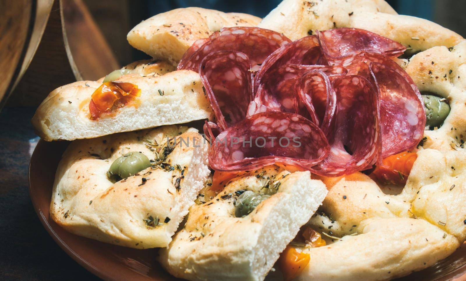 Plate of focaccia bread with slices of salami and olives by tennesseewitney