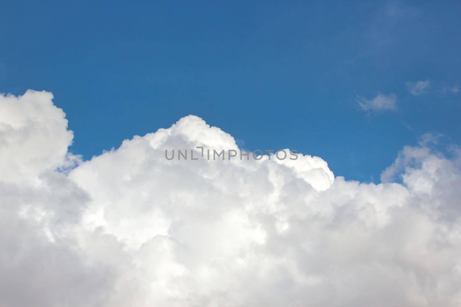 Big fluffy white clouds against a bright clear blue sky background