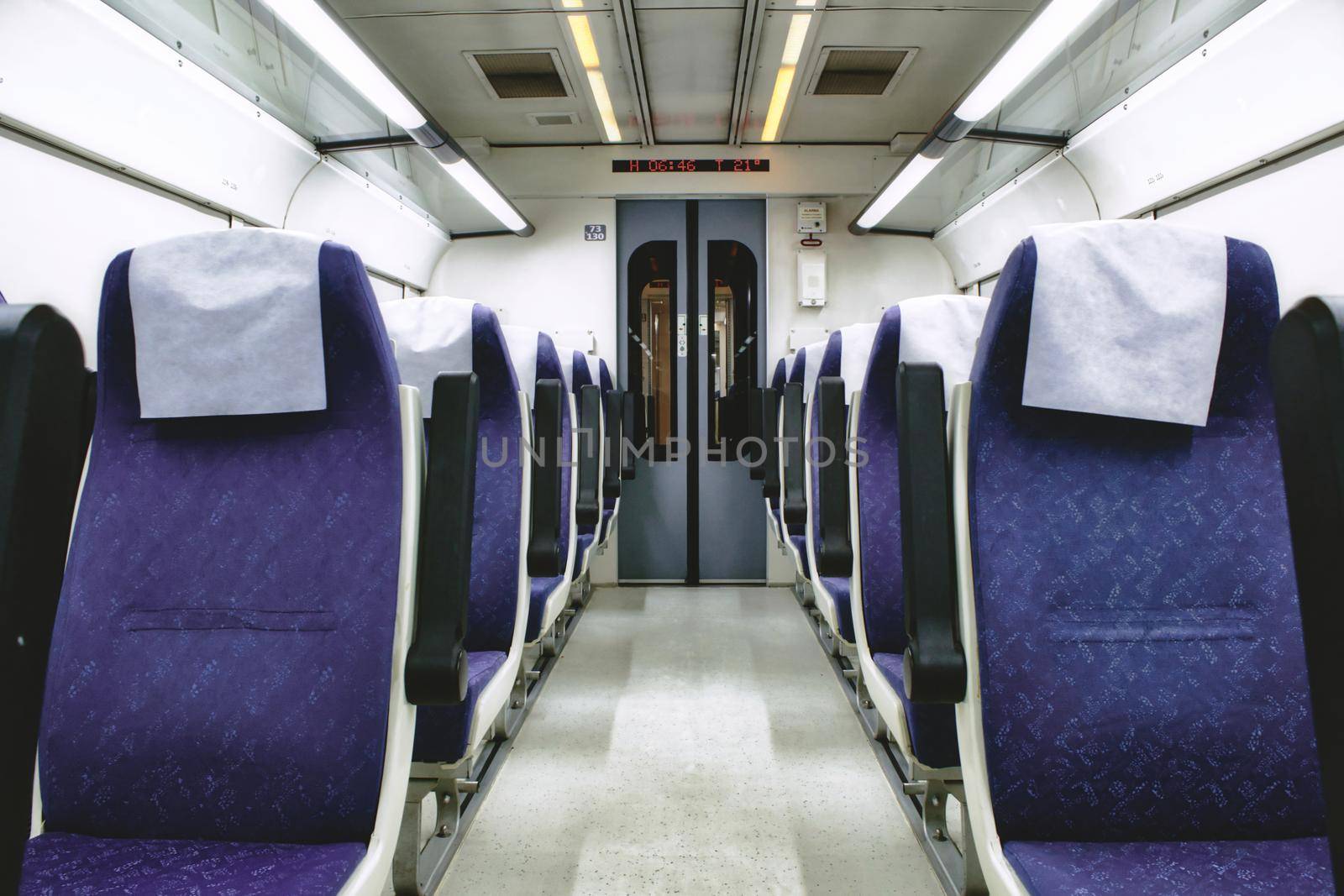 Interior of train carriage between rows of empty chairs