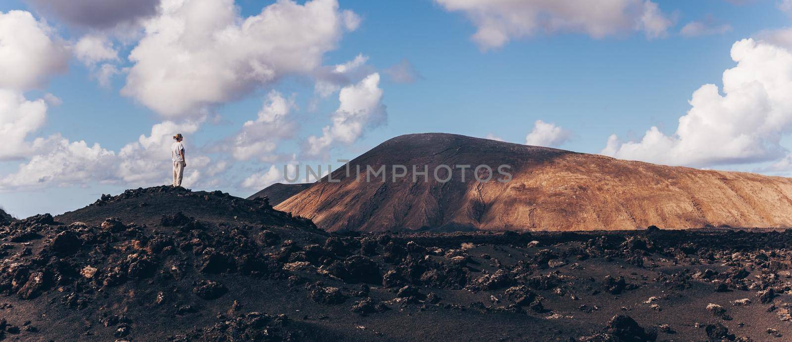 Female tourist enjoying amazing views of volcanic landscape in Timanfaya national park on Lanzarote, Spain. Freedom and travel adventure concept