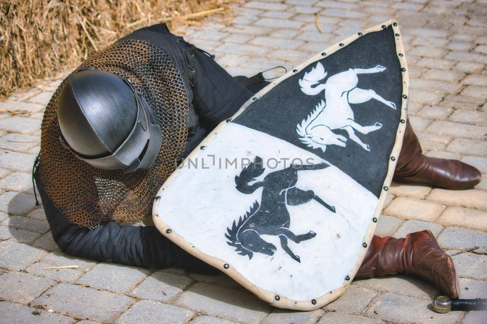 A medieval knight in full body armour lying injured on the ground