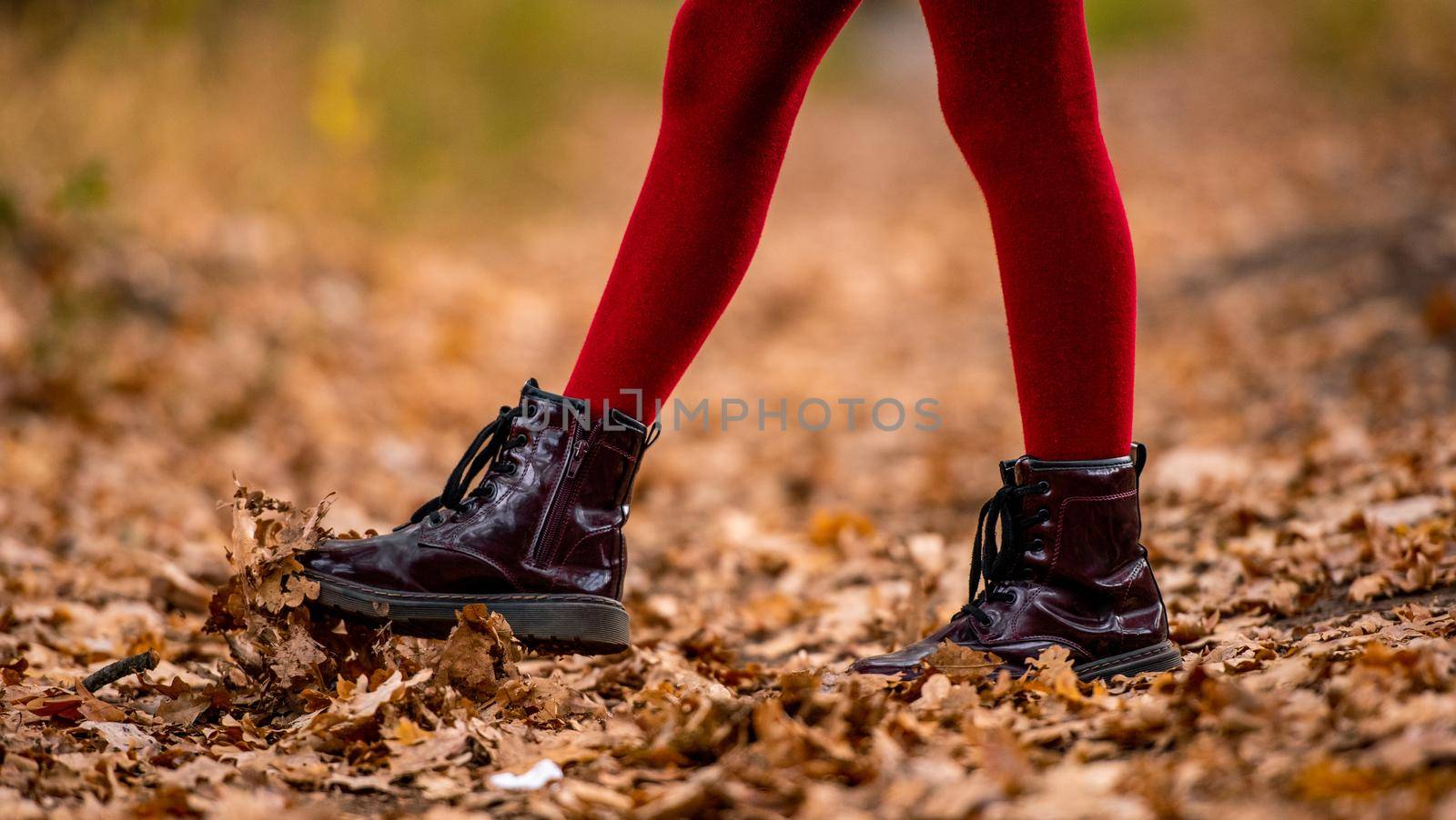 Preteen girl kid with golden retriever dog walking at autumn park at road covered with yellow leaves. Beautiful portrait of child and pet outdoors at nature from back