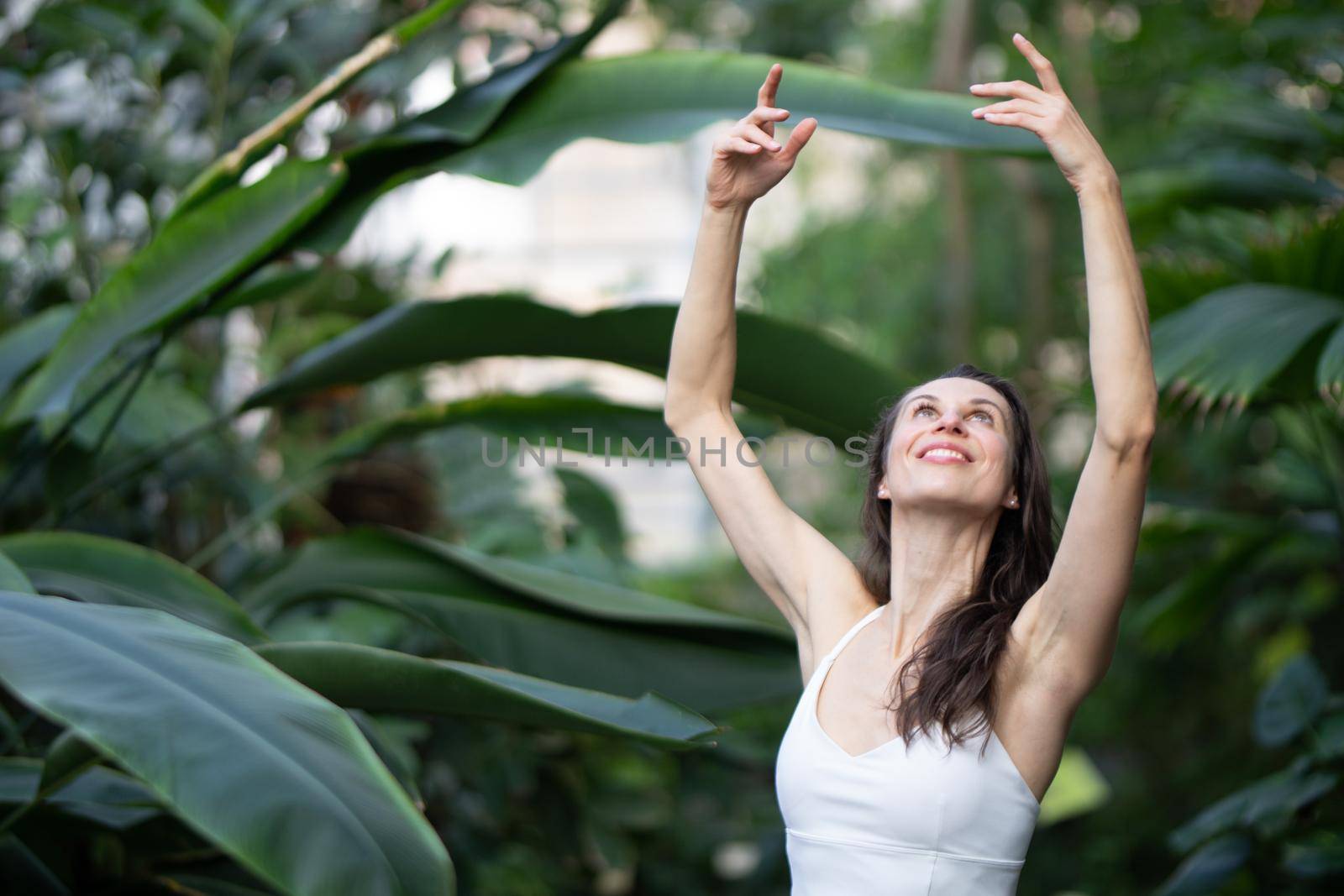 Female meditating and practicing yoga in tropical rainforest. Beautiful young woman practicing yoga outdoor with tropical forest in background. by kasto