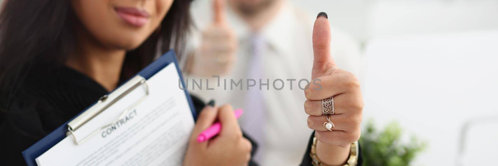 A woman holds a contract and shows an ok gesture, close-up, blurry. Meeting to sign a cooperation agreement