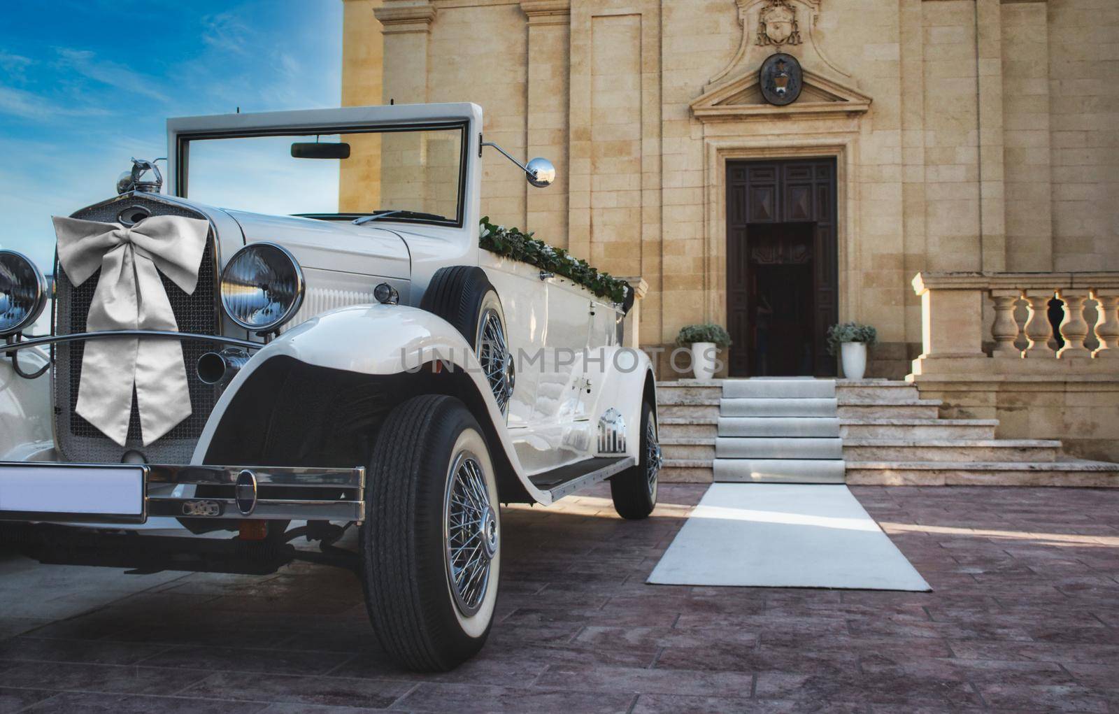 Qarb / Malta - November 24 2019: White classic car for a traditional wedding in front of a church by tennesseewitney