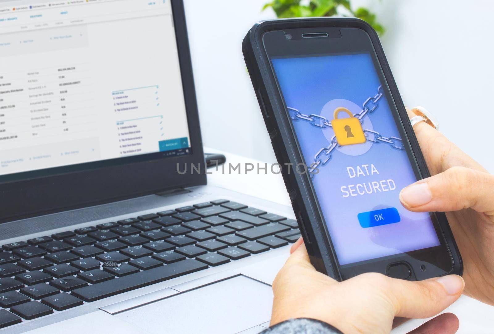Woman holding a mobile smart phone with a data security application displaying a yellow padlock and pressing OK button with finger