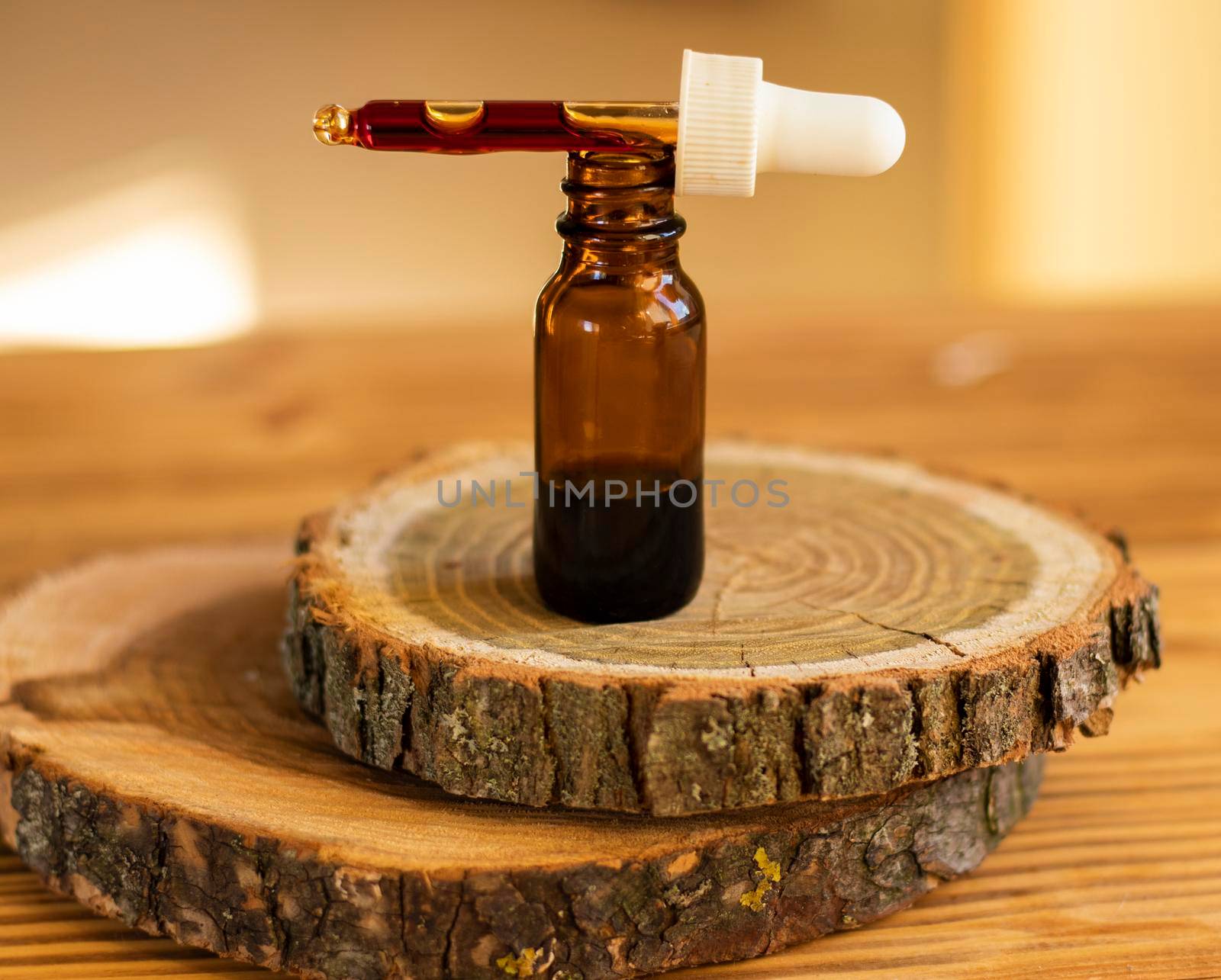 a drop of serum with pipette drips over a brown glass jar on wooden background close-up. selective focus. beauty concept. natural cosmetic. Daily skin care. Anti-aging serum with natural ingredients