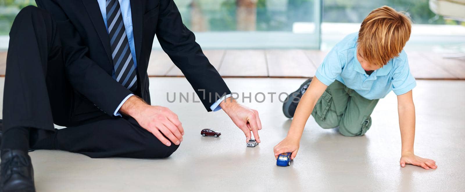 A little boy playing with his father on the floor.