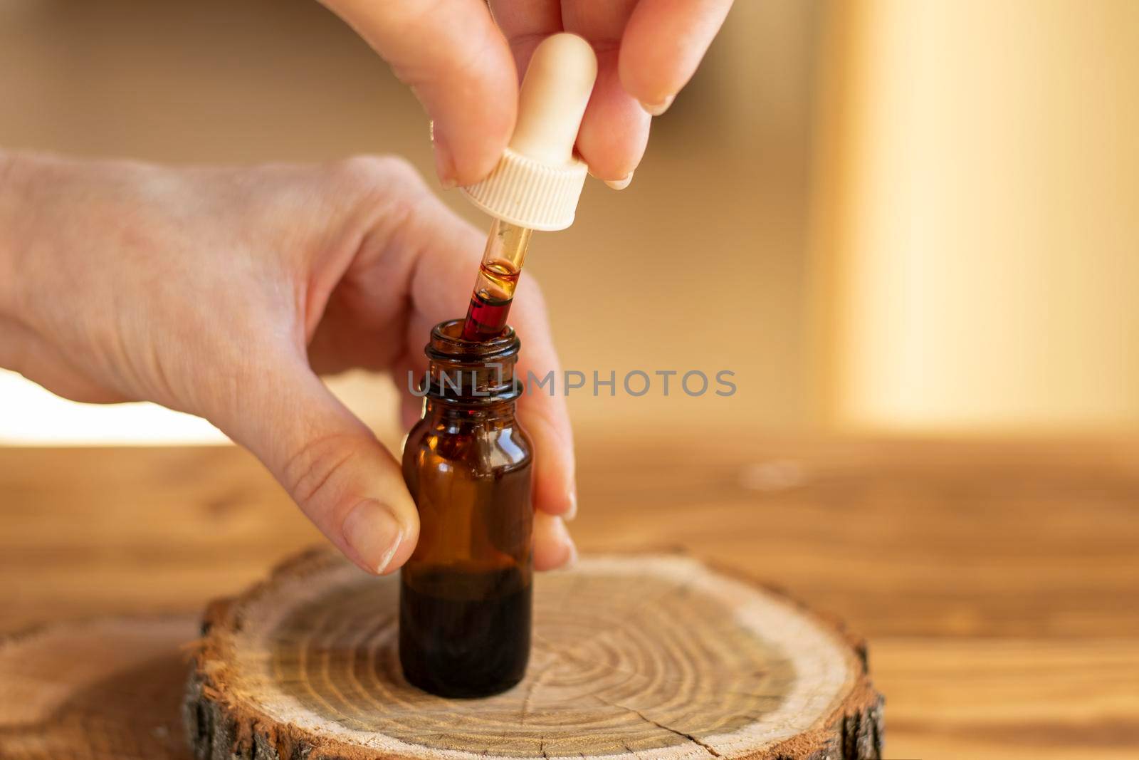 a drop of serum with pipette drips over a brown glass jar on wooden background close-up. selective focus. beauty concept. natural cosmetic. Daily skin care. Anti-aging serum with natural ingredients