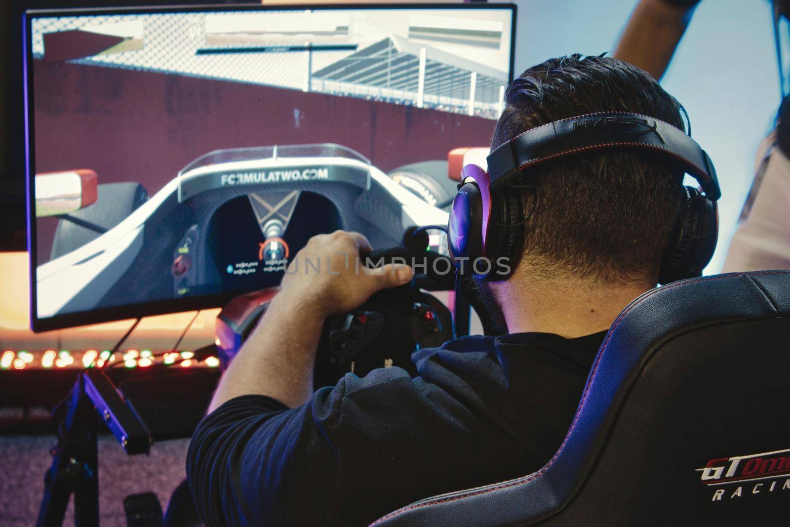 Mosta / Malta - May 11, 2019: A man playing a virtual reality racing game with steering wheel and headphones at a gadget fair by tennesseewitney