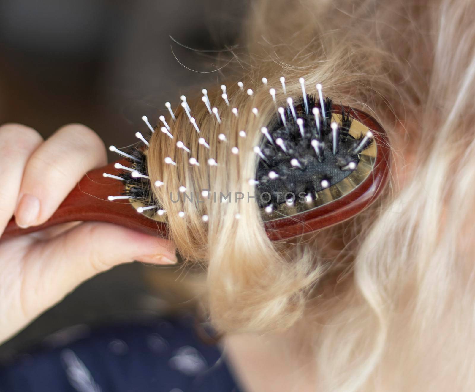 selective focus. blond combing wet and tangled hair. Young woman combing her tangled hair after shower, close-up. High quality photo